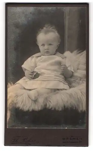 Fotografie Th. Rohse, Bremen, Waller Chausee 31 d, Süsses Kleinkind im Kleid mit Ball sitzt auf Fell