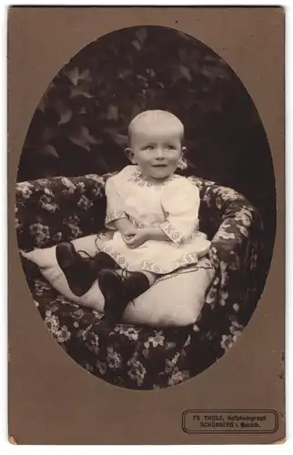 Fotografie Fr. Thiele, Schönberg i. Mecklb., Kleines Kind im Kleid sitzt auf Kissen