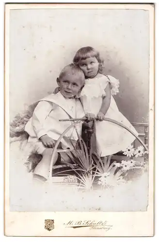 Fotografie M. B. Schultz, Flensburg, Norderhofenden 13, Kleines Mädchen und Junge in hübscher Kleidung mit Reifen