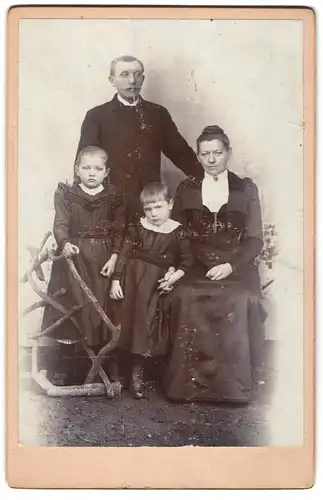 Fotografie unbekannter Fotograf und Ort, Ernst blickende Familie mit zwei Kindern im Sonntagsstaat