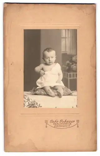 Fotografie Gebrüder Gebauer, Karlsruhe i. B., Schillerstrasse 13, Ernst blickendes Baby auf einem Kissen