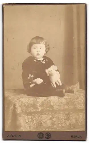Fotografie J. Fuchs, Berlin, N. Reinickendorferstrasse 4, Kleines Kind mit Stofftier auf einem Sitzmöbel