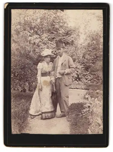 Fotografie unbekannter Fotograf und Ort, Dame im Kleid neben Herren mit Zylinder