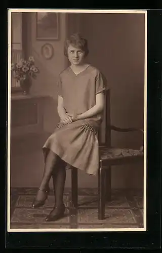 Foto-AK Junge Dame im Kleid auf Armlehne sitzend in Studiokulisse
