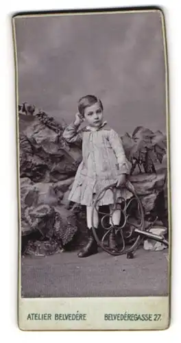Fotografie Atelier Belvedere, Ort unbekannt, Belvederegasse 27, Kind mit kurzen Haaren im Kleid vor exotischer Kulisse