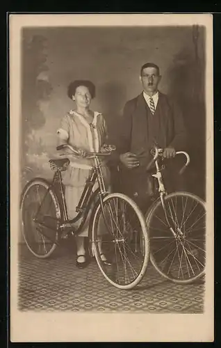 Foto-AK Bürgerliches Paar in einer Studiokulisse mit ihren zeitgenössischen Fahrrädern
