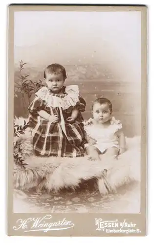 Fotografie H. Weingarten, Essen a. Ruhr, Limbeckerplatz 8, Zwei junge Mädchen im Kleid sitzen auf Schaffellen