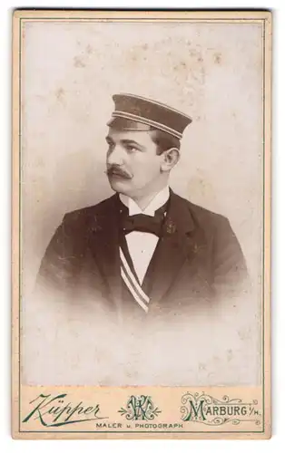 Fotografie Küpper, Marburg i. H., Student im Anzug mit Couleur und Schnauzbart, Schirmmütze