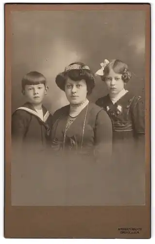 Fotografie Wilhelm Rauch, Bruck a. d. M., Mutter mit ihren beiden Kindern samt gestylten Haaren im Atelier