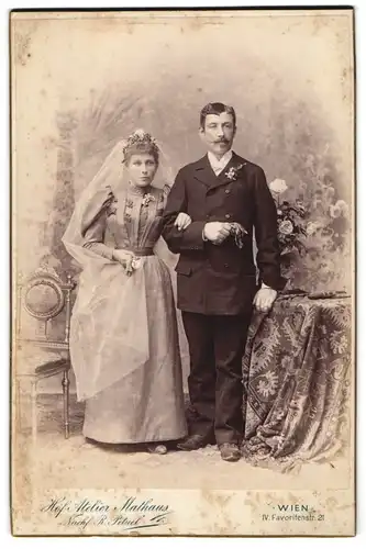 Fotografie Rudolf Petuel, Wien, Brautpaar im hellen Hochzeitskleid mit Schleier und im Anzug mit Ansteckblume