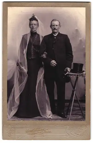 Fotografie Carl Hansen, Niebüll, älteres Brautpaar im schwarzen Hochzeitskleid und Anzug mit Zylinder