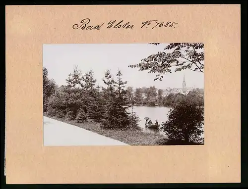 Fotografie Brück & Sohn Meissen, Ansicht Bad Elster, Ruderboot auf dem Luisa-See, Kirchturm im Hintergrund