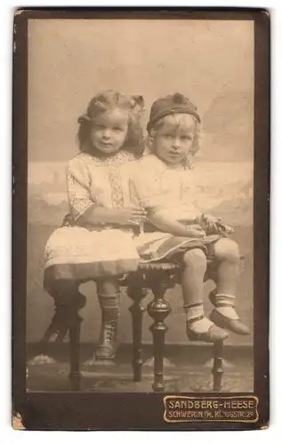 Fotografie Sandberg-Heese, Schwerin, Königstr. 29, 2 Junge Mädchen in Kleidern auf kleinem Tisch