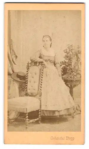 Fotografie Gebrüder Bopp, Innsbruck, Dame in langem Kleid an dekorativem Stuhl mit hoher Lehne