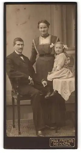 Fotografie Max Freitag, Meissen, Mutter und Vater mit ihrer Tochter im Kleid auf einem Tisch sitzend, Mutterglück
