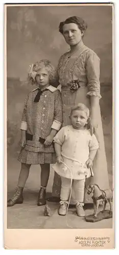 Fotografie Adolph Richter, Leipzig-Lindenau, Mutter neben ihren zwei Kindern mit Spielzeugpferd, Mutterglück