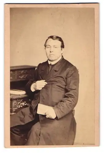 Fotografie F. Jungmann, Tetschen, Schiffsgasse Nr. 173, Geistlicher mit Gebetsbuch am Sekretär sitzend