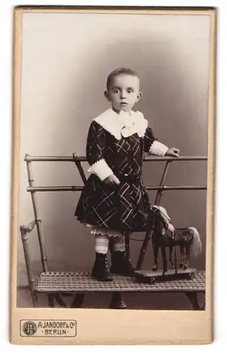 Fotografie A. Jandorf & Co., Berlin, Kleines Kind im Kleid mit Spielzeugpferd