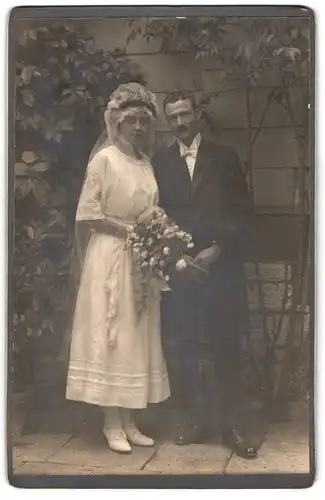 Fotografie unbekannter Fotograf und Ort, Brautpaar im Kleid und Anzug mit Blumenstrauss