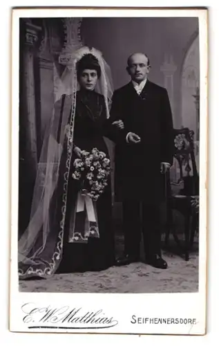 Fotografie E. W. Matthias, Seifhennersdorf, Frisch vermähltes Brautpaar im schwarzen Kleid und im Anzug