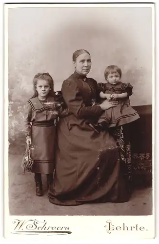 Fotografie W. Schroers, Lehrte, Mutter neben ihren zwei Kindern in Kleidern, 1895