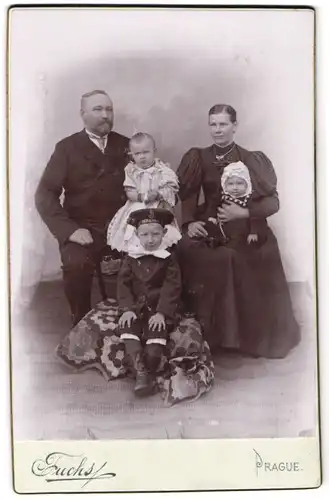 Fotografie Fuchs, Prague, Mutter im langen Kleid mit Puffärmeln neben ihrem Mann und ihren drei Kindern, Mutterglück