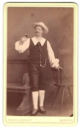 Fotografie Klotz & Bscher, Kempten, Mann als Weinkönig in Tracht mit erhobenem Glas im Atelier