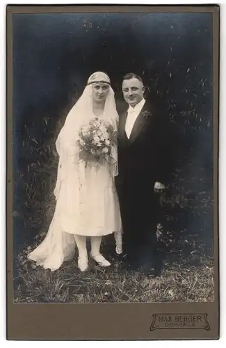 Fotografie Max Berger, Dohna i. S., Brautpaar im weissen Kleid mit Blumenstrauss und Schleier im Grünen