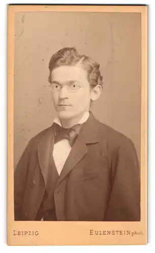Fotografie Eulenstein, Leipzig, Zeitzerstr. 34, Junger Mann in modischem dunklem Anzug mit Brille