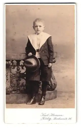 Fotografie Karl Hansen, Görlitz, Berlinerstr. 26, Bub in zeitgenössischer Kleidung mit Hut in der Hand