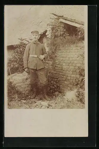 Foto-AK Soldat in Uniform mit Krätzchen vor einem Haus