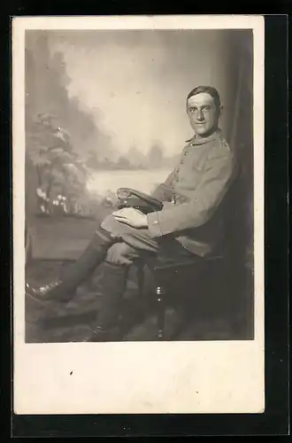 AK Soldat sitzend in einer Fotokulisse, Uniformfoto