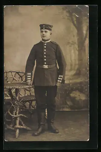 AK Soldat stehend im Fotostudio, Uniformfoto