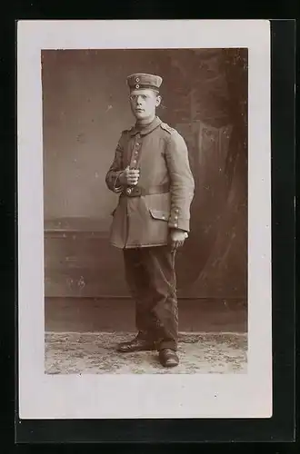 AK Soldat steht in Uniform, mit Schirmmütze