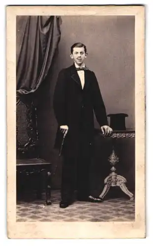 Fotografie unbekannter Fotograf und Ort, Portrait junger Mann im dunklen Anzug mit Zylinder und Flanierstock