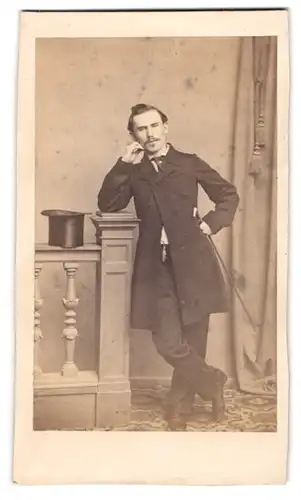 Fotografie unbekannter Fotograf und Ort, Portrait junger Mann im feinen Anzug nebst Zylinder und Flanierstock, 1863