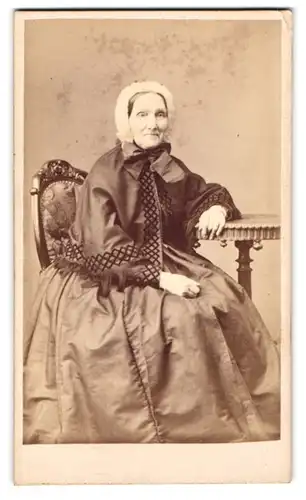 Fotografie L. Herzog, Bremen, ältere Dame im Reifrockkleid mit Haube und Bolero posiert im Atelier