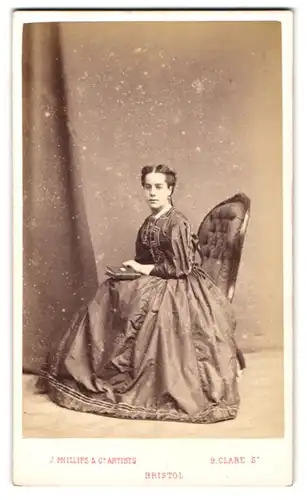 Fotografie J. Phillips & Co., Bristol, junge Engländerin im seidenen Biedermeierkleid mit Fotoalbum in der Hand