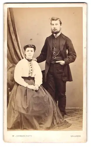 Fotografie W. Johnson, Bradford, Englisches Paar in seitgenössischer Kleidung posiert im Atelier