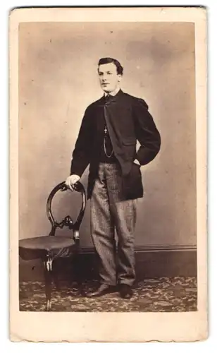 Fotografie Stanley, Coventry, junger Mann im Anzug posiert stehend am Stuhl