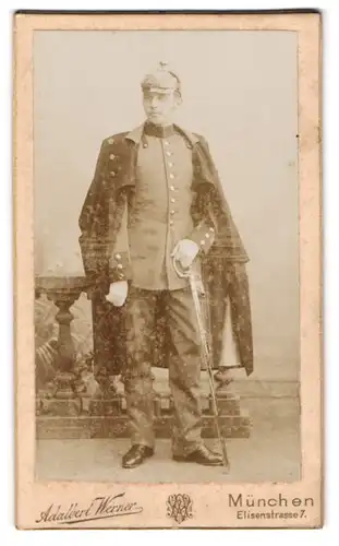 Fotografie Adalbert Werner, München, Soldat in Uniform mit Mantel und Pickelhaube, Säbel