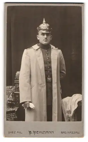 Fotografie B. Mehlmann, Diez a. L., Portrait Soldat in Uniform mit Mantel und Pickelhaube