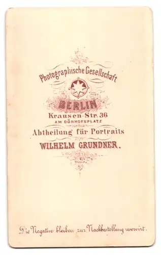 Fotografie Wilhelm Grundner, Berlin, Krausen-Str. 36, junge Frau im schlichten dunklen Kleid stehend am Sekretär