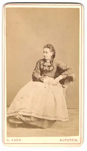 Fotografie A. Karg, Kufstein, junge Frau im dunklen Kleid mit Schürze und geflochtenen Haaren