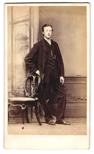 Fotografie J. Ashley, Retford, junger Mann im dunklen Anzug posiert stehend am Stuhl