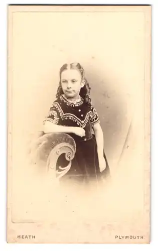 Fotografie William Heath, Plymouth, kleines Mädchen im dunklen bestickten Kleid mit Locken lehnt an einem Sessel