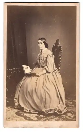Fotografie Groom & Co., Plymouth, Dame im hellen Biedermeierkleid mit Fotoalbum in der Hand