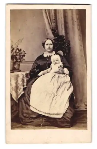 Fotografie unbekannter Fotograf und Ort, Portrait Mutter im dunklen Kleid mit Kleinkind im weissen Kleidchen