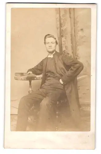 Fotografie W. J. Wellsted, Hull, Portrait junger Engländer im Anzug mit heller Fliege sitzt lässig im Atelier