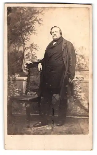 Fotografie unbekannter Fotograf und Ort, Portrait korpulenter Herr im schwarzen Anzug posiert stehend im Atelier